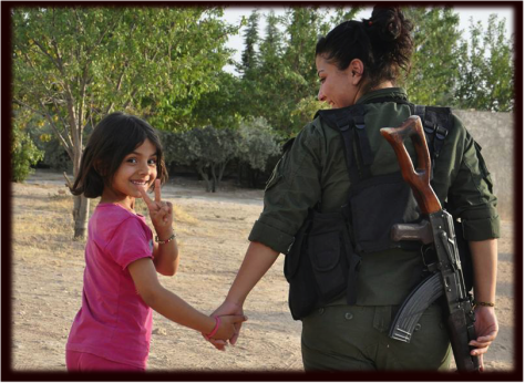 A girl rescued from ISIS terror in Manbij is welcomed by a revolutionary YPJ volunteer.